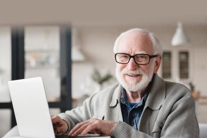 older man with beard and glasses on laptop